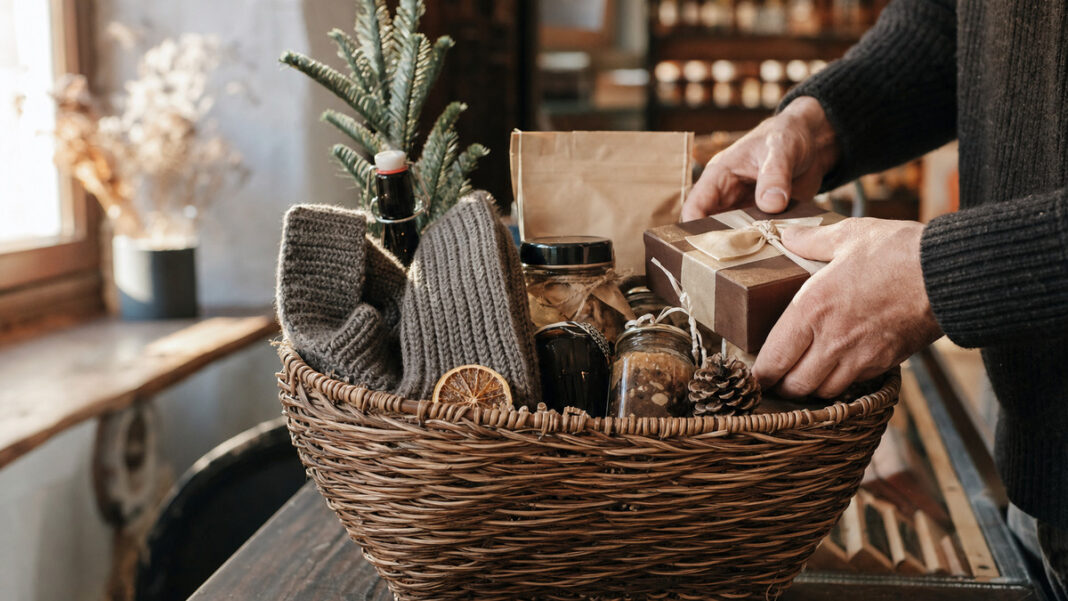 Geschenkekorb mit winterlichen Überraschungen in einer Berliner Manufaktur, Hände legen ein Präsent dazu
