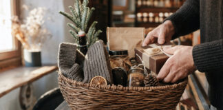 Geschenkekorb mit winterlichen Überraschungen in einer Berliner Manufaktur, Hände legen ein Präsent dazu