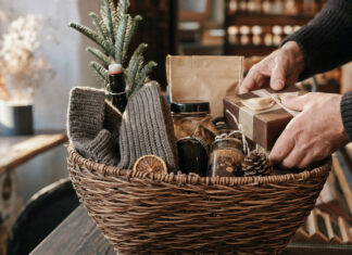 Geschenkekorb mit winterlichen Überraschungen in einer Berliner Manufaktur, Hände legen ein Präsent dazu