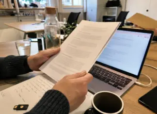 Hände prüfen einen AVV und Datenschutzunterlagen auf einem Schreibtisch.