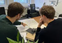 Zwei Gründer vergleichen Unterlagen und eine Regionskarte für ihren DeepTech-Transfer.