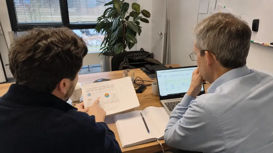 Zwei Mitarbeitende planen einen messbaren KI-Piloten an einem Besprechungstisch.
