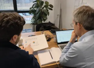 Zwei Mitarbeitende planen einen messbaren KI-Piloten an einem Besprechungstisch.