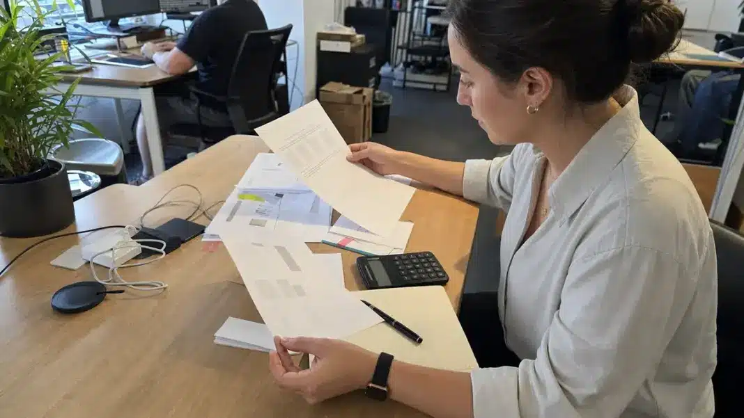 Hände prüfen Freelancer-Rechnungen und Verträge für die Künstlersozialabgabe im Startup.