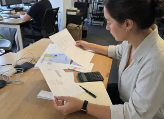 Hände prüfen Freelancer-Rechnungen und Verträge für die Künstlersozialabgabe im Startup.