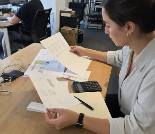 Hände prüfen Freelancer-Rechnungen und Verträge für die Künstlersozialabgabe im Startup.