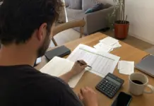 Gründerin prüft einen Liquiditätsplan mit Kalkulation, Notizen und Taschenrechner am Arbeitsplatz.
