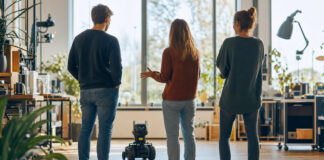 Team schaut sich im Makerspace einen kleinen Lernroboter an