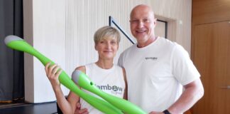 Die Ajambow-Gründer Susan Schmidt und Simon Werner halten je einen grünen, wassergefüllten Ajambow-Bogen