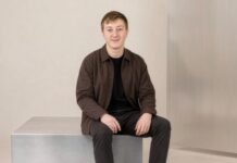 Clarity School: Wie Moritz Zinecker neben seiner App eine UG gründete Moritz Zinecker, Gründer von Audecius, sitzt in brauner Jacke auf einem Metallblock vor heller Wand