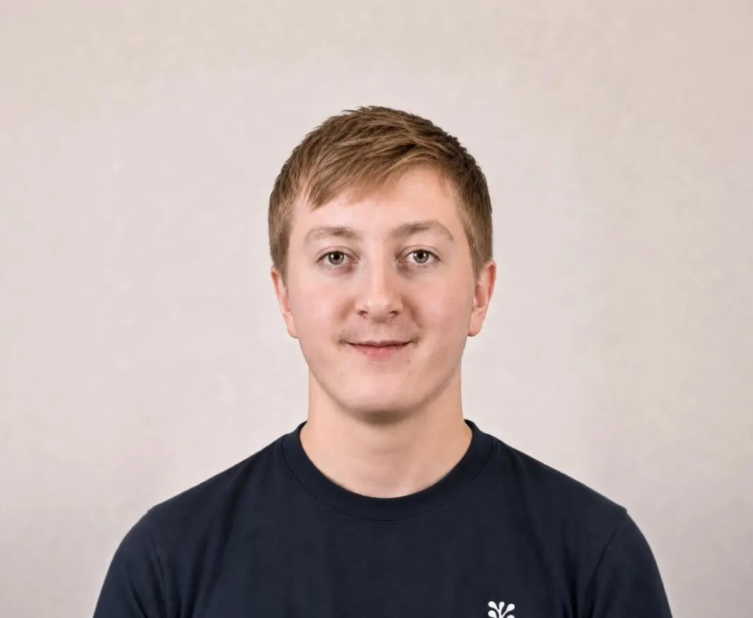 Porträt von Moritz Zinecker in dunkelblauem T-Shirt vor hellem Hintergrund