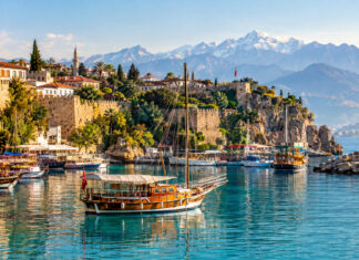 Der alte Hafen Kaleiçi in Antalya mit Holzbooten, Stadtmauer und dem Taurusgebirge im Hintergrund