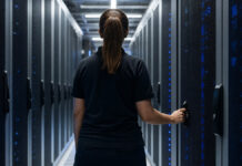 Technikerin schließt im Rechenzentrum eine vergitterte Server-Tür ab