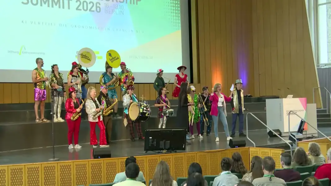 Die Band Gertrude in bunten Kostümen mit Blasinstrumenten auf der Bühne des Audimax zum Auftakt des Entrepreneurship Summit 2026