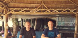 Die blookery-Gründer Kevin Kiesewetter und Jannis Jäger sitzen auf einem Sofa unter einem Bambusdach