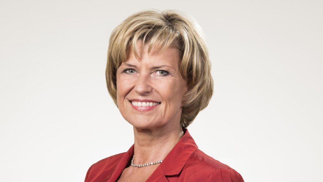 Dagmar Wöhrl lächelt in roter Jacke vor hellem Hintergrund, Porträt aus dem Jahr 2012