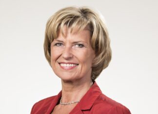 Dagmar Wöhrl lächelt in roter Jacke vor hellem Hintergrund, Porträt aus dem Jahr 2012