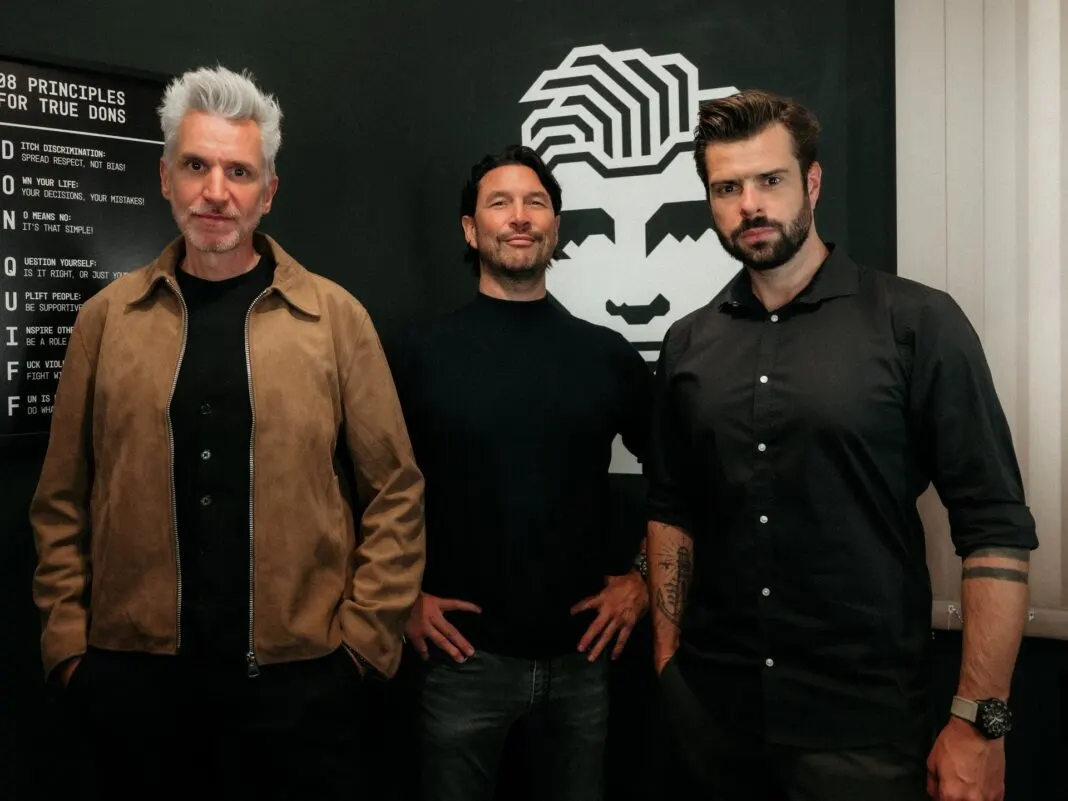 Die drei Don-Quiff-Gründer Robert Tarquini, Max Kögl und Klaus Laimer stehen vor dem Markenlogo