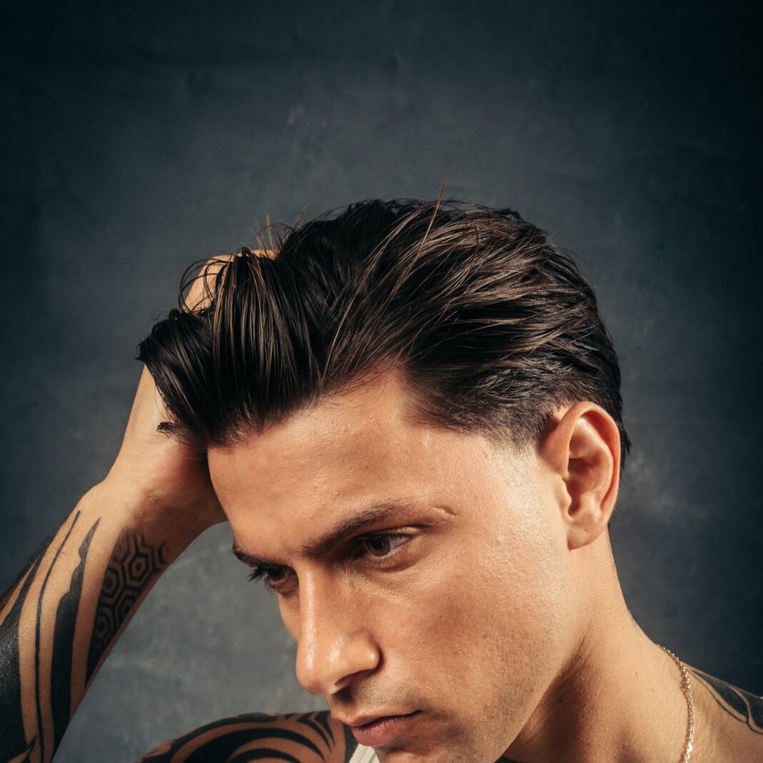 Ein Mann streicht sich das nach hinten gestylte Haar aus der Stirn, Werbefoto der Marke Don Quiff