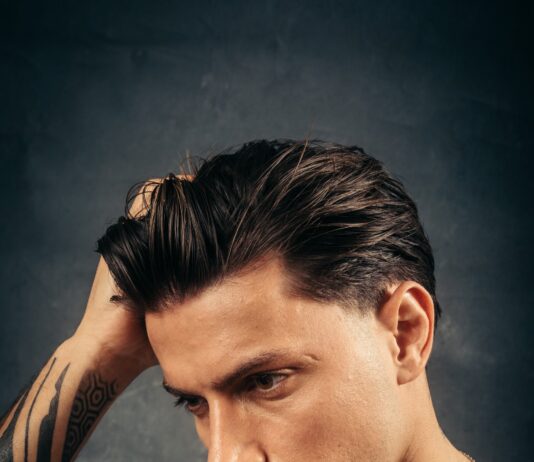Ein Mann streicht sich das nach hinten gestylte Haar aus der Stirn, Werbefoto der Marke Don Quiff