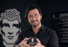 Gruender Robert Tarquini haelt eine schwarze Dose Don Quiff Energy Wax in seinem Salon in die Kamera