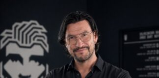 Gruender Robert Tarquini haelt eine schwarze Dose Don Quiff Energy Wax in seinem Salon in die Kamera