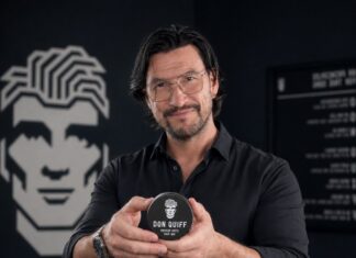 Gruender Robert Tarquini haelt eine schwarze Dose Don Quiff Energy Wax in seinem Salon in die Kamera