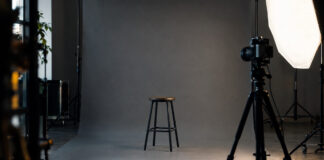 Leeres Fotostudio mit grauem Hintergrund, Hocker, Kamera auf Stativ und Lichtschirm