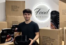 Emre Tuncer hält eine schwarze Springform, um ihn stehen Versandkartons und verpackte Backformen von Food with Style vor dem beleuchteten Firmenschild