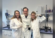 Die drei Gründer von FoodFor in Laborkitteln im Labor, zwei halten Bechergläser