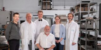 Das Team von HEIONTEC steht in einer Werkhalle, einer der Gründer sitzt im Rollstuhl