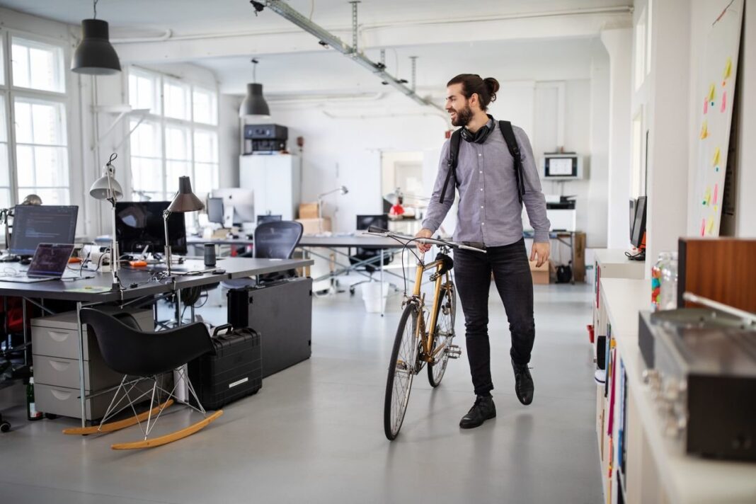 Mitarbeiter schiebt sein Fahrrad zum Feierabend durch das Büro