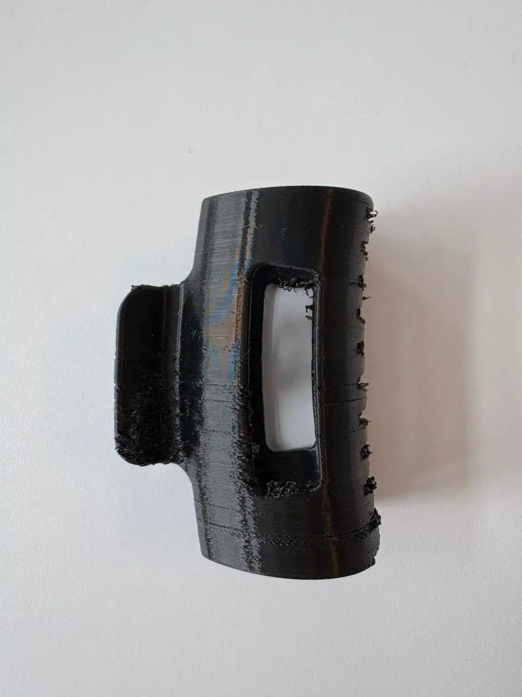 Schwarzer 3D-gedruckter Prototyp der Haarklammer mit sichtbaren Druckschichten auf hellem Untergrund