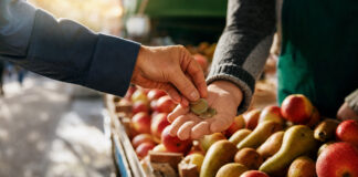 Kundin bezahlt am Obststand, Münzen wechseln die Hand