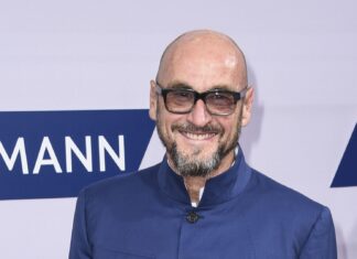 Jochen Schweizer mit Brille und blauer Jacke lächelt auf einem roten Teppich, 2016