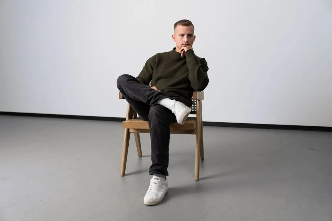 Johannes Kliesch, Mitgründer von SNOCKS, sitzt auf einem Holzstuhl in einem hellen Studio