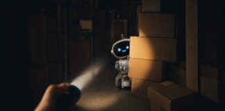 Taschenlampe entdeckt einen kleinen Roboter hinter Kartons im Lager
