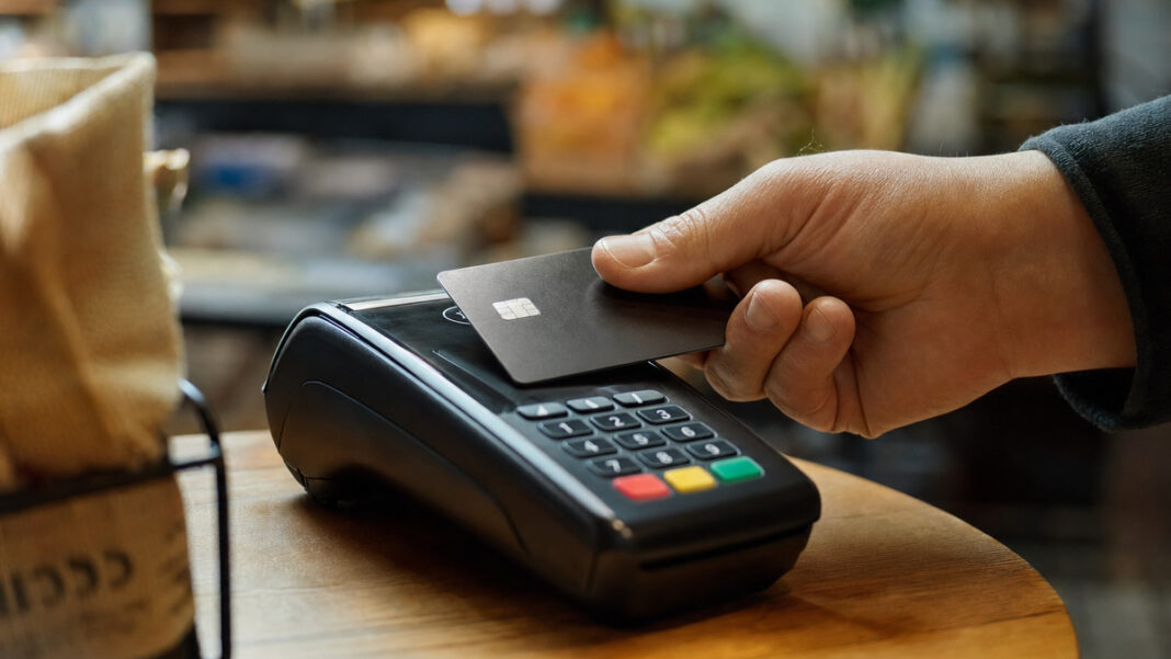 Kleingewerbe und Steuern: was wirklich fällig wird Kontaktlose Kartenzahlung an einem Bezahlterminal, eine Hand hält die Karte an das Lesefeld