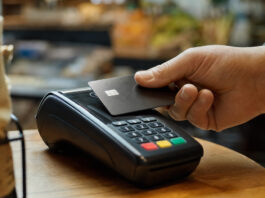 Kontaktlose Kartenzahlung an einem Bezahlterminal, eine Hand hält die Karte an das Lesefeld