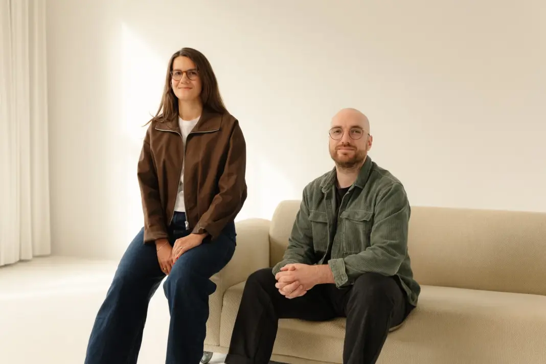 Die Kuro-Gründer Lea Scherer und Jonas Minkler in einem hellen Raum an einem Sofa