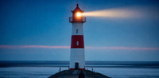 Leuchtturm an der Nordsee sendet in der blauen Stunde seinen Lichtstrahl