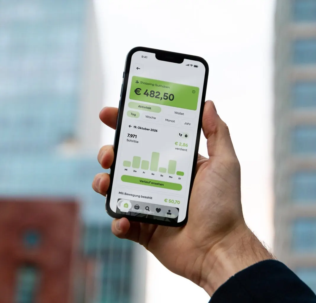 Eine Hand hält ein Smartphone mit der move2pay App, die Schritte und Shopping Guthaben anzeigt