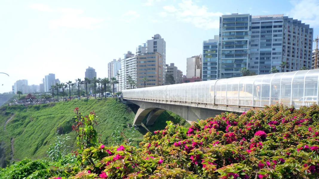 Brücke über die begrünte Schlucht in Miraflores mit Wohntürmen und blühenden Sträuchern