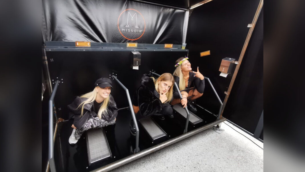 Missoir bei der Höhle der Löwen: Urinal für Frauen, ganz ohne Wasser Drei Festivalbesucherinnen hocken nebeneinander in einem mobilen Missoir mit Haltegriffen und Spritzschutz