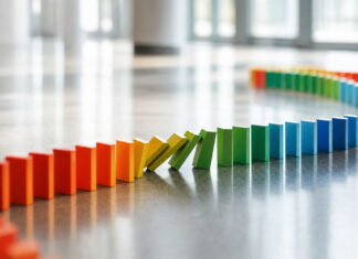 Lange Reihe bunter Dominosteine fällt kettenartig um