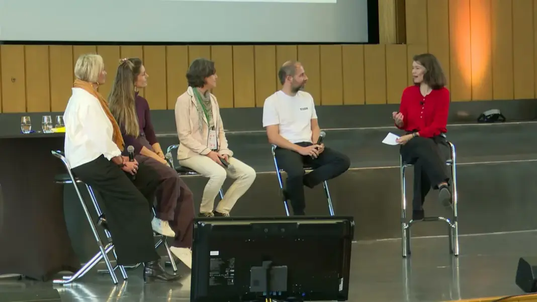 Fünf Personen sitzen auf Stühlen auf der Bühne des Audimax beim Panel David gründet, Goliath lobbyiert