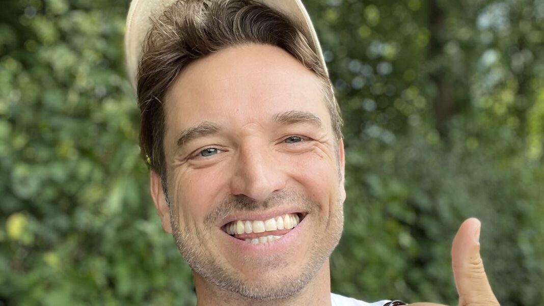 Pinkoa Gründer Laurens Laudowicz Laurens Laudowicz mit heller Kappe lacht vor grünem Laub und zeigt den Daumen nach oben