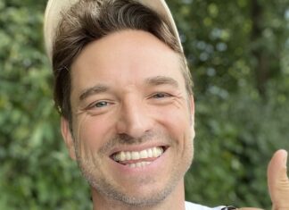 Laurens Laudowicz mit heller Kappe lacht vor grünem Laub und zeigt den Daumen nach oben