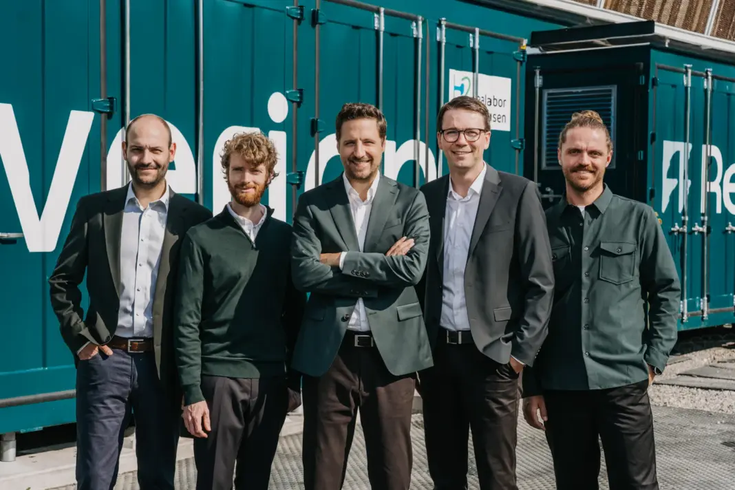 Die fünf Gründer von Reverion stehen vor einem Brennstoffzellenkraftwerk im Container