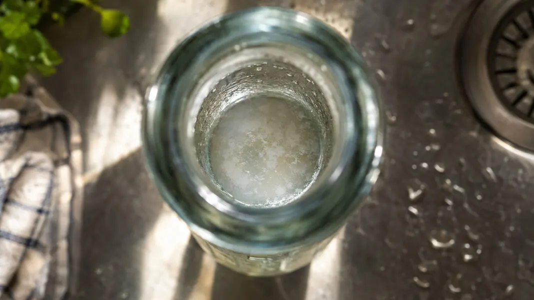 Blick in eine geöffnete Trinkflasche mit trübem Belag am Boden